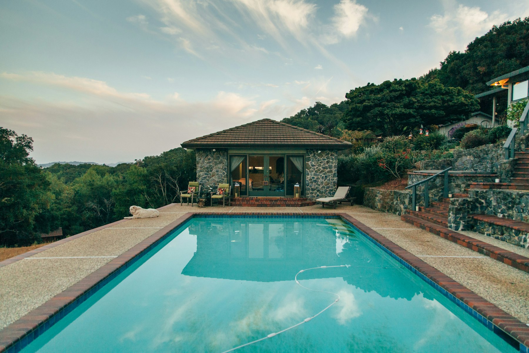 Piscine au crépuscule devant mas provençal en pierre